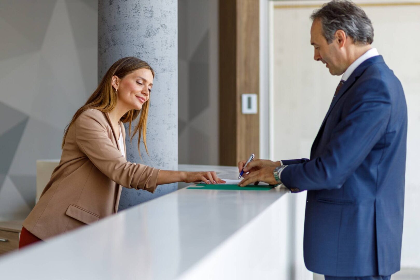 Man signing document at a reception desk.